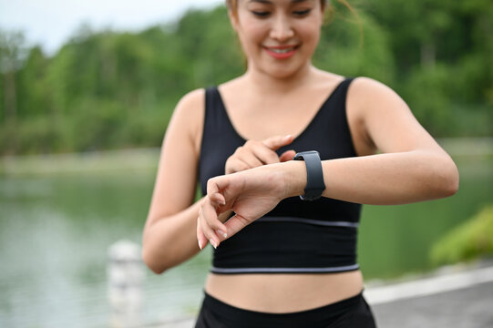 Close-up image of a sporty Asian woman checking her calories burned on her smartwatch