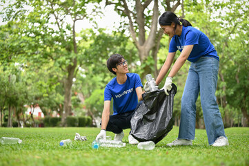 Smiling Asian male and female volunteers with a plastic garbage bag clean up the public park