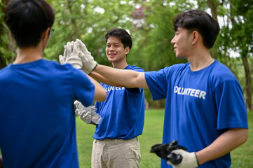 A group of cheerful young Asian volunteers join hands together or give high fives