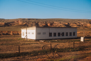 a lonely brick building in a sunny morning desert with hills