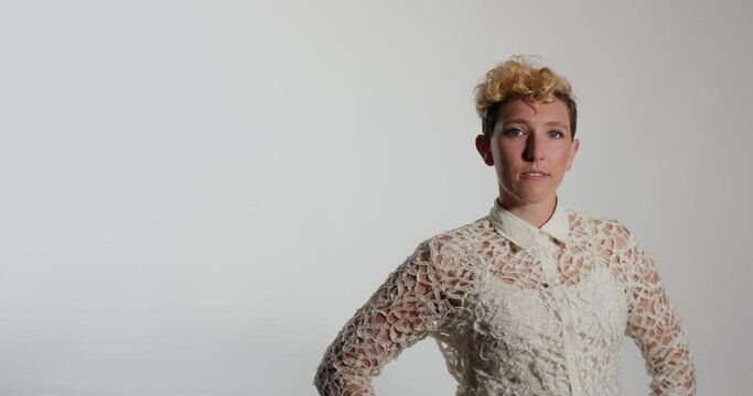 A nonbinary person poses against a white backdrop, expressing a range of relaxed, casual, smiling portraits.