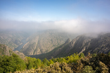 aerial view with a drone from the top of the canyon with the mountains on the sides of the river and thick fog above them