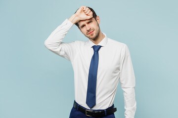 Young sick ill sad employee business man corporate lawyer wear classic formal shirt tie work in office put hand on forehead suffer from headache isolated on plain pastel light blue background studio.