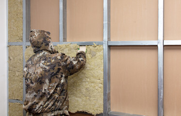 Workers insulate the wall in the room