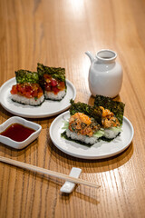 Japanese opened hand sushi rolls with different fish and sauce on table