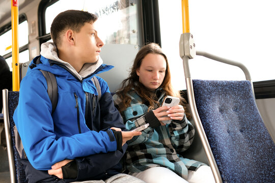 two teenagers in blue clothes sit on bus Canada Vancouver hoods autumn winter spring tracksuits use a mobile phone search for geolocation travel travelers real life