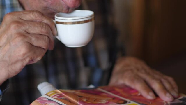 a pensioner drinks coffee and reads an adult magazine while looking at photos of naked women. leisure active elderly man drinking tea from a cup