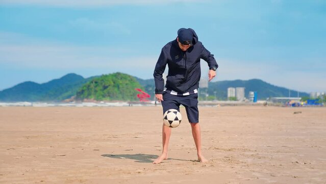 Young man training football freestyle. Adult man playing with a soccer ball on the beach. Athlete with the dream of being a football player.