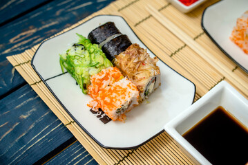 Several sushi on a white plate standing on a brown background

