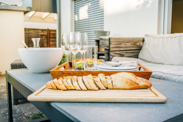Freshly baked baguette with healthy snack and glasses on terrace or patio