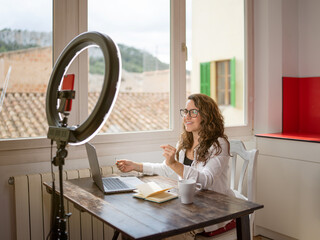 A beautiful woman with glasses conducting a video conference using her mobile phone and a ring...