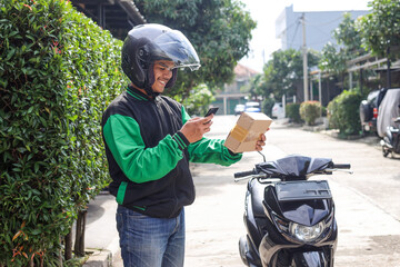 Asian man work as a commercial motorcyle delivery courier scanning barcode on the package