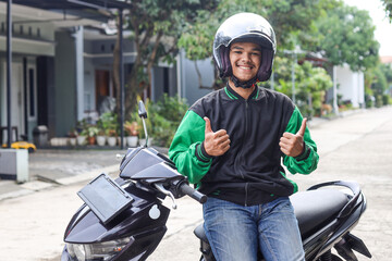 Asian man work as a commercial motorcyle taxi driver smiling while giving his thumb up