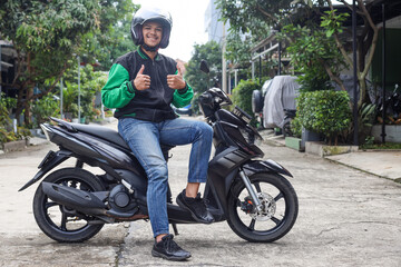 Asian man work as a commercial motorcyle taxi driver smiling while giving his thumb up 