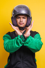 Asian online taxi driver wearing green jacket and helmet crossing hands, gesturing say no warning...