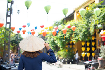 Tourist woman is wearing Non La (Vietnamese tradition hat) and enjoy sightseeing at Heritage village in Hoi An city in Vietnam.