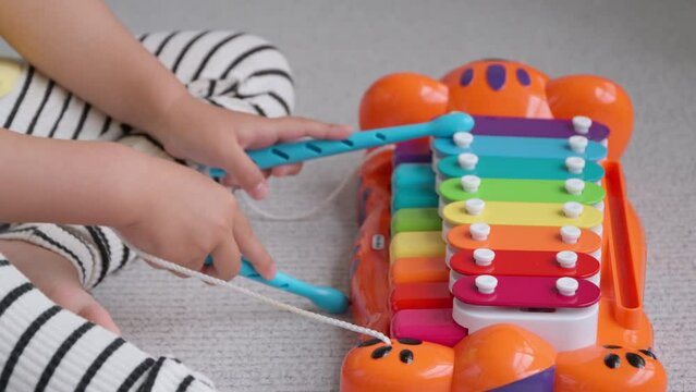 Little Girl's Hands Playing on Toy Piano Tikes Jungle Jamboree Tiger Xylophone At Home Sitting on Floor - close up slow motion