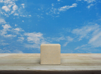 Wood block cube on wooden table over blue sky with white clouds