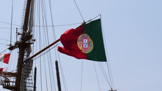 Handheld shot of waving Portuguese flag on marine ship on Oporto during windy day,close up