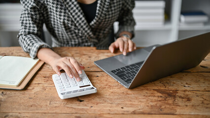 Cropped image of a businesswoman using a calculator and working on her tasks on her laptop