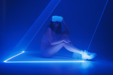 Woman with futuristic tablet in hand. Girl in glasses of virtual reality presses the start button. Augmented reality game, future technology, AI concept. Holographic interface to display data.