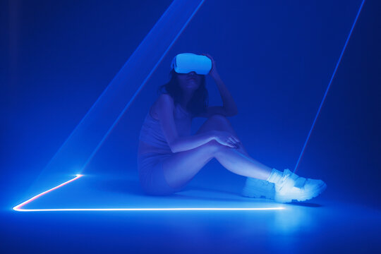 Woman with futuristic tablet in hand. Girl in glasses of virtual reality presses the start button. Augmented reality game, future technology, AI concept. Holographic interface to display data.