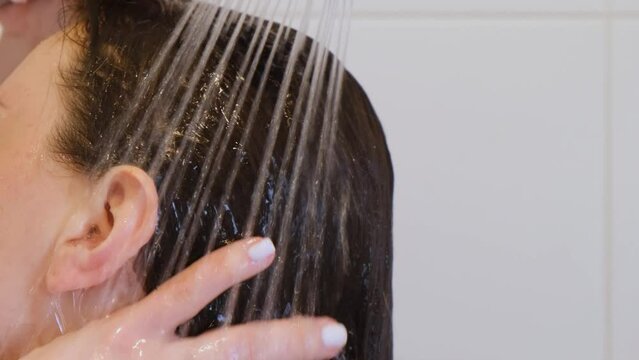 A woman washes her hair in the shower. Close-up.