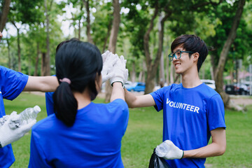 Volunteers of various nationalities are showing solidarity, donating their personal time, holding black trash bags to collect plastic waste for recycling to reduce pollution in a public park.
