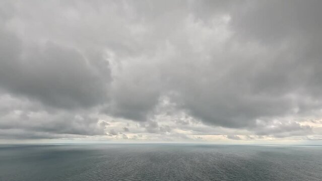 Timelapse of dark rain clouds moving in overcast grey sky over a sea horizon during bad weather. Abstract aerial nature ocean sunset sea and sky. Rainy weather. Climate change, global warming concept