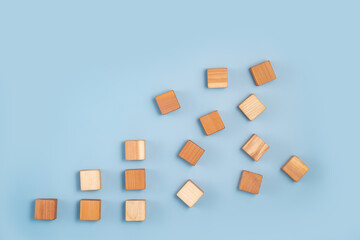 Fototapeta na wymiar blank wooden cubes scattered in shades ranging from dark to light beige on blue background. Minimalistic abstract concept representation of progress and diversity. Top view flat lay copy space