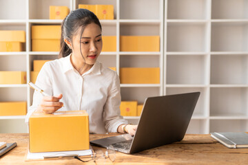 starting a small business SME Business Owner Asian female entrepreneur works on receipt boxes and checks online orders to prepare boxes for sale to customers who order online.