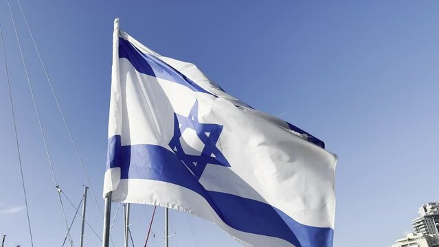 Israeli flag white and blue with star Magen David fluttering in wind on blue sky. outdoor. 