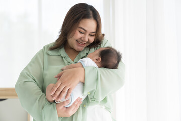 Newborn baby sleeping during mother carrying. Asian mother take care her newborn on hands with kindness. family, love, happy and new life concept