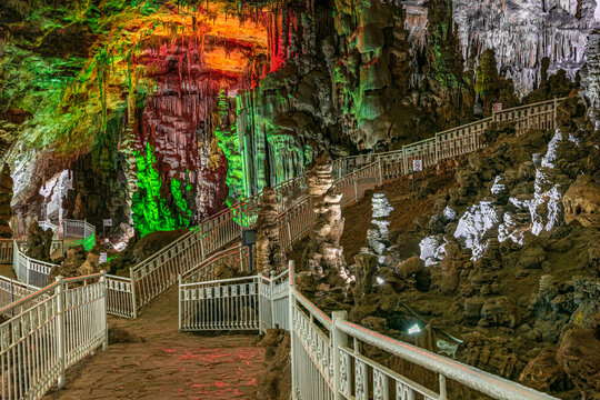 Beni Add cave, Ain Fezza, Tlemcen, Algeria. Interior view with its marvelous stalagmites and stalactites. White ramp for the pedestrian walkway path and rocks in green, orange, white and purple colors