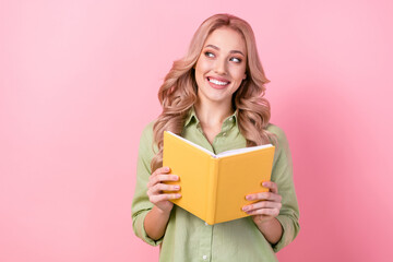 Photo of clever positive minded lady hold opened book look empty space isolated on pink color...