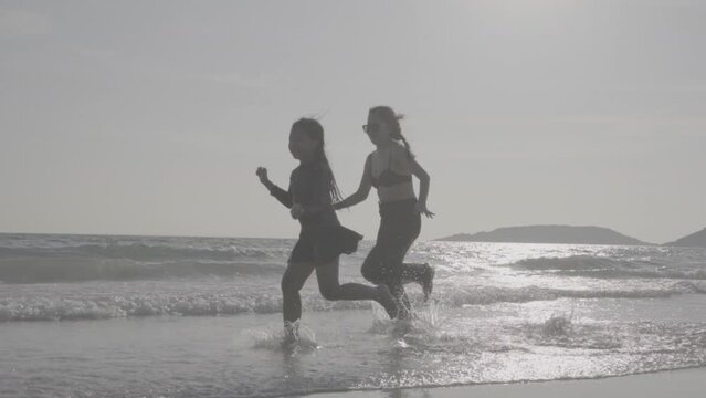 Family mother and daughter run jumping  at sea bleach