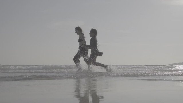 Family mother and daughter run jumping  at sea bleach