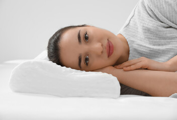 Woman lying on orthopedic memory foam pillow indoors