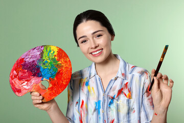 Fototapeta premium Woman with painting tools on pale green background. Young artist