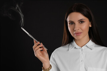 Woman using long cigarette holder for smoking on black background, space for text
