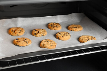 Baking delicious chocolate chip cookies in oven, closeup