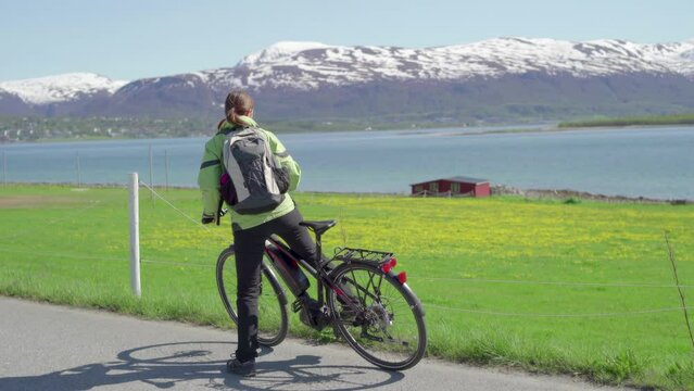 Urlauberin steigt vom Fahrrad ab und genießt Landschaft