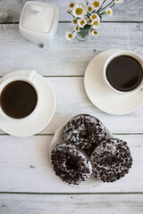 Chocolate donuts with cup of coffee. on white wooden table.