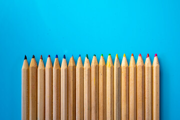 Lápices de colores de madera sobre mesa azul listos para época escolar.