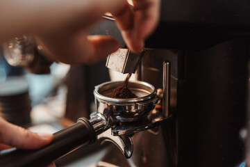 Coffee grinder grinds fresh coffee beans into a portafilter for  espresso machine. Barista grind...