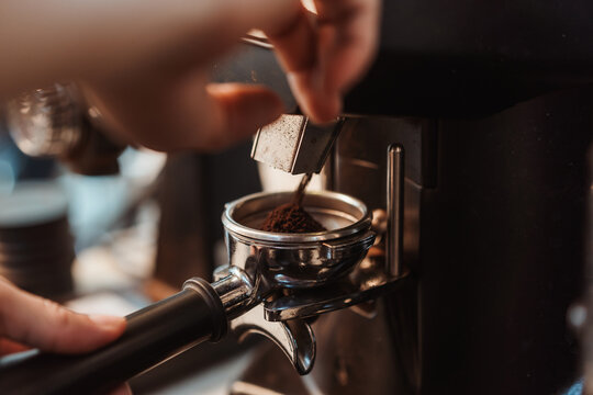 Coffee grinder grinds fresh coffee beans into a portafilter for  espresso machine. Barista grind coffee bean with grinder machine. Selective focus.