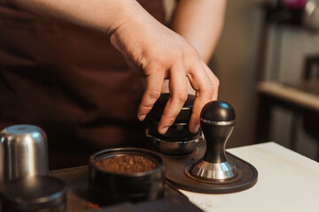 Fototapeta na wymiar Closeup hand of barista preparation tampering coffee in portafilter for making espresso. Coffee making concept.