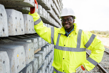 Portrait of railroad construction worker standing by concrete sleepers.