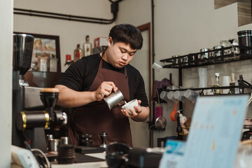 Barista pouring milk foam to making latte art coffee. Asian man barista working at coffee shop. Latte art menu coffee, Espresso, Coffee menu making concept.