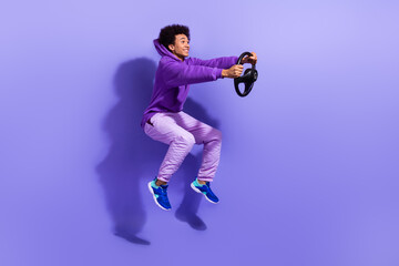 Full length photo of cheerful funky look empty space hold steering wheel riding on invisible car isolated on violet color background